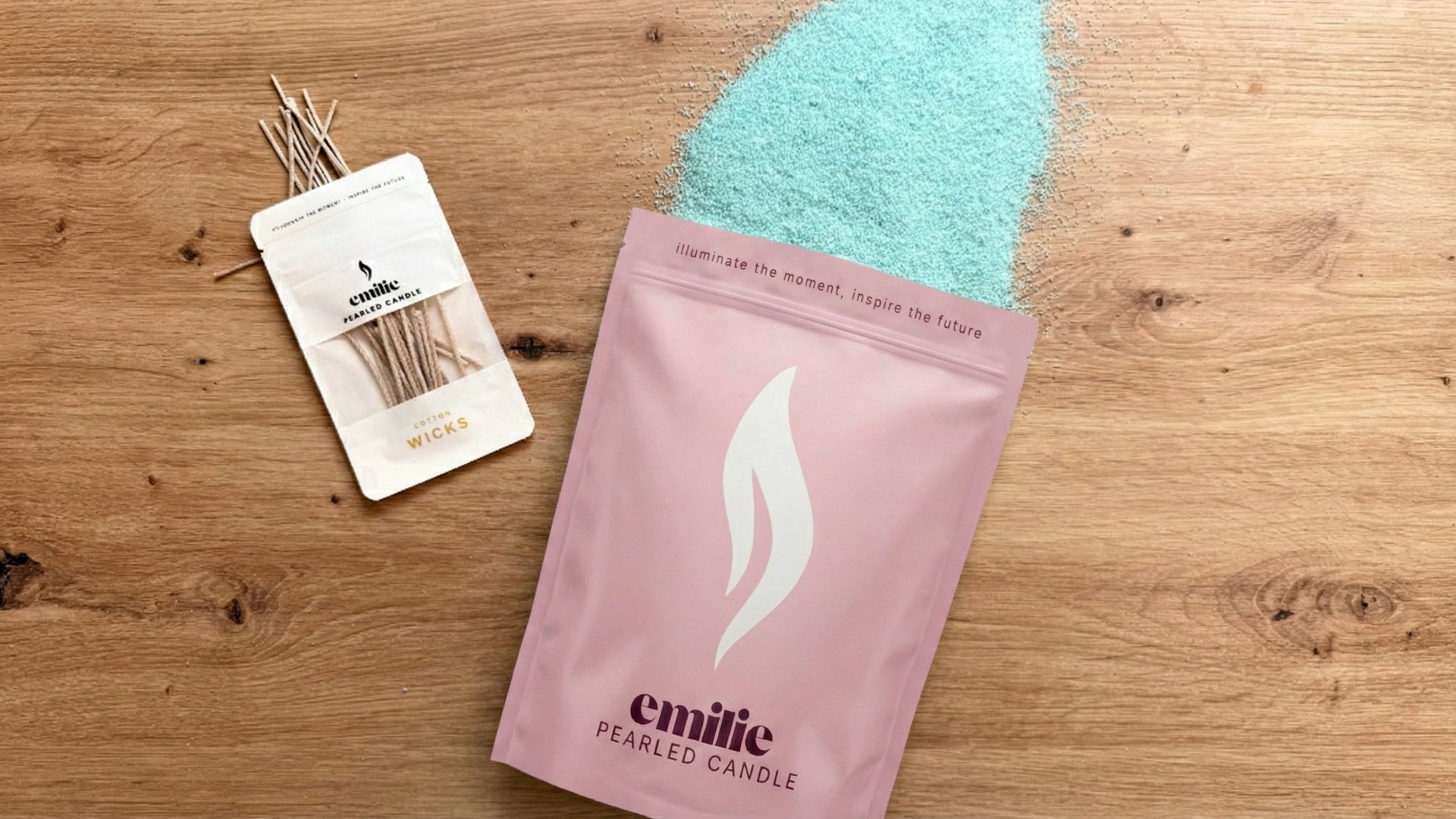 Pink package of emilie scented candles with a small white pouch bag with wicks on a wooden surface