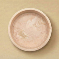 pink ceramic bowl with a textured beige interior on a matching beige background