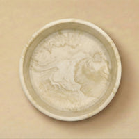 Round ceramic dish with a textured surface on a beige background