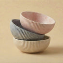 Three ceramic bowls of different colors stacked on a beige background