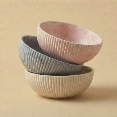 Three ceramic bowls of different colors stacked on a beige background