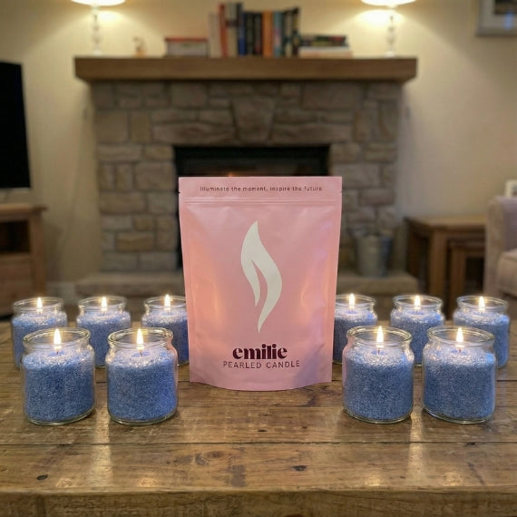 Blue pearled candles with a pink emilie candle packaging on a wooden surface, fireplace in the background