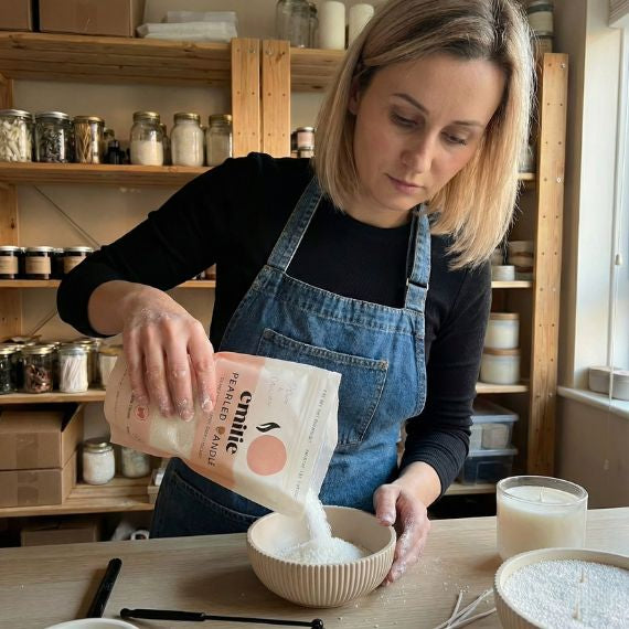 founder of emilie pearled candle  in a workshop, pouring test pearled candle from a bag into a bowl.